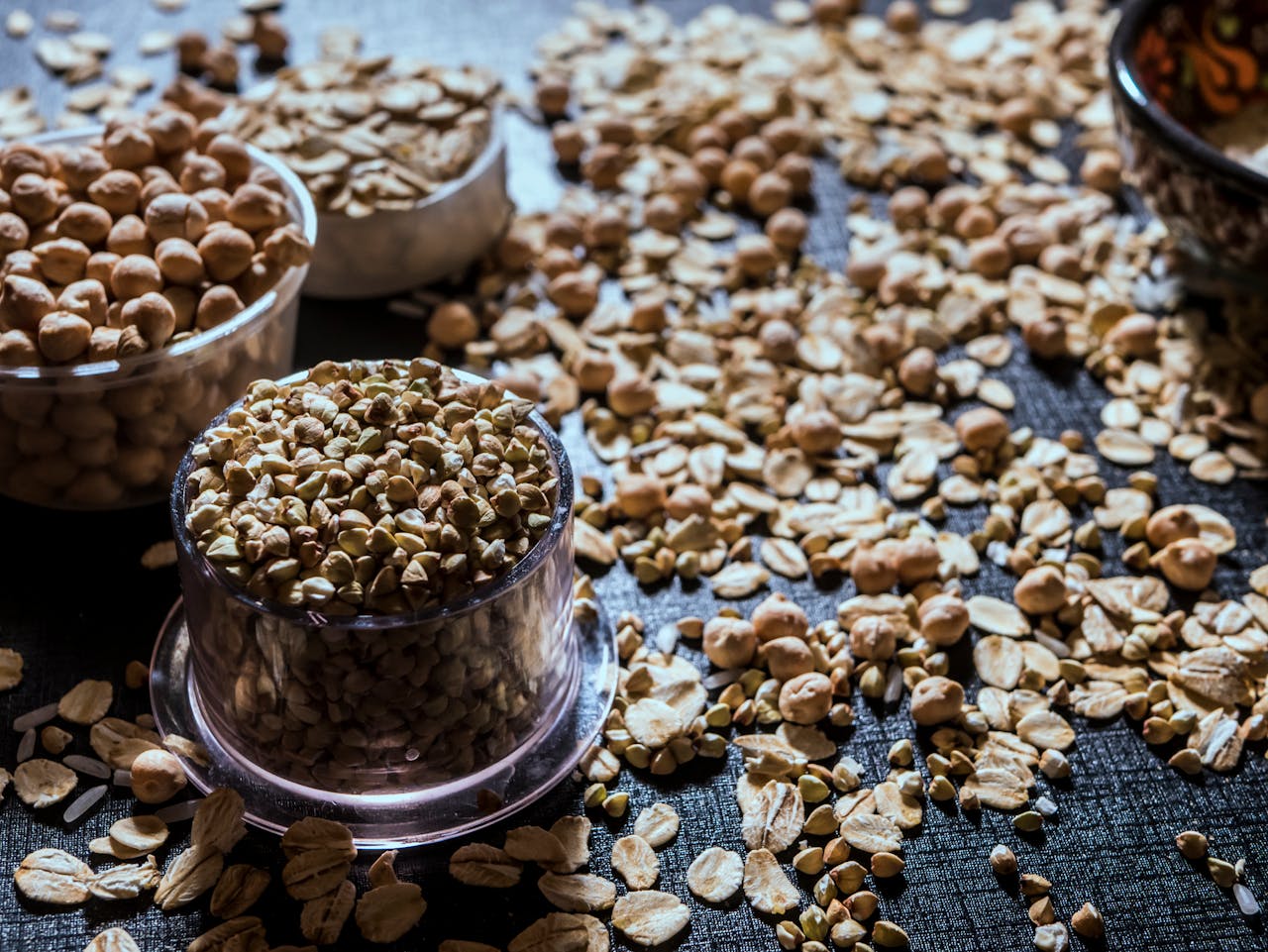 Close-up of diverse grains and legumes in plastic cups on a textured surface, highlighting healthy food options.