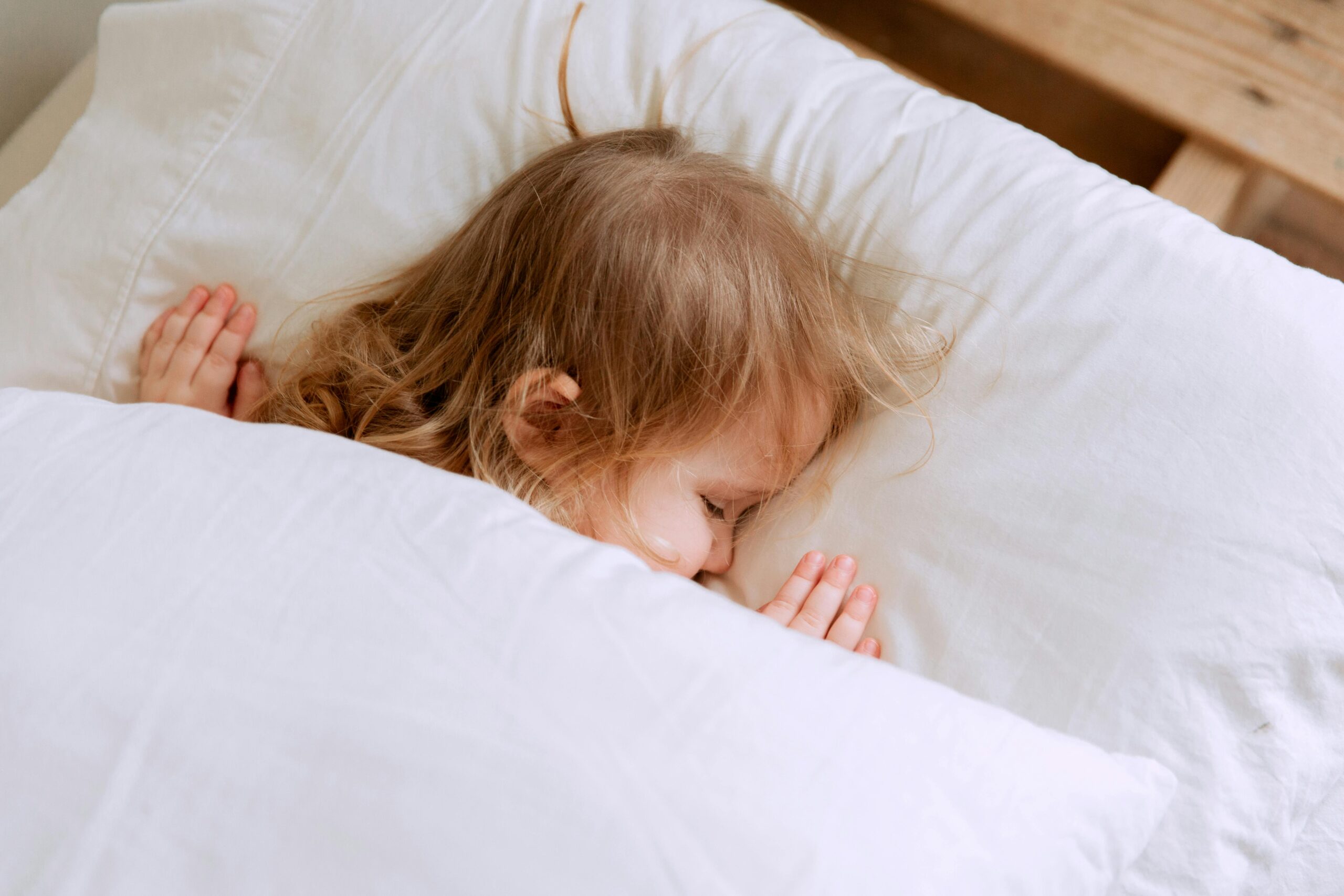 A young child peacefully sleeping under white blankets, embodying innocence and serenity.