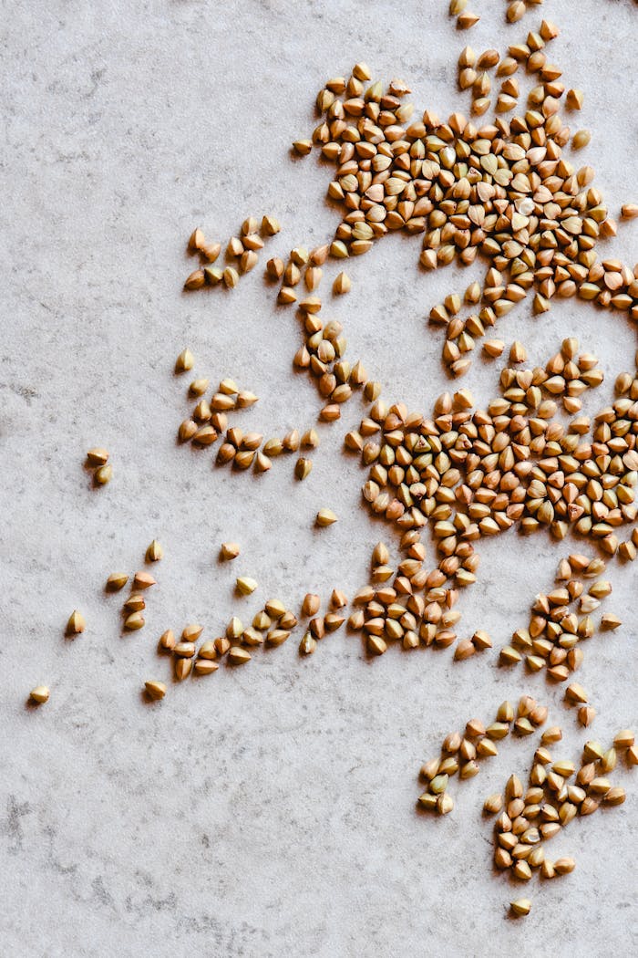 Raw buckwheat grains scattered on a light surface, emphasizing texture.